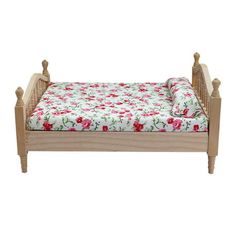 a small wooden bed with pink flowers on the sheets and headboard, in front of a white background