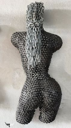 a black and white sculpture with chains on it's back, in the shape of a man