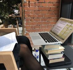 a woman sitting at a table with a laptop and books on her lap