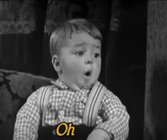 a little boy sitting on top of a couch in front of a sign that says oh