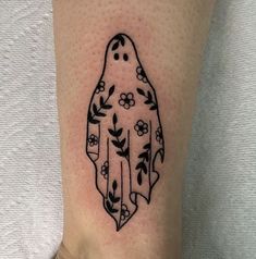 a black and white photo of a ghost with flowers on it's leg tattoo