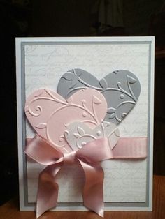 a card with two hearts on it and a pink ribbon tied around the heart shape