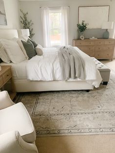 a large white bed sitting in a bedroom on top of a wooden dresser next to a window