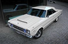 an old white car is parked in front of a building