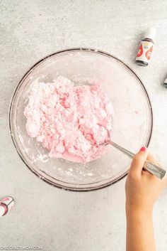 a person mixing food in a bowl with a measuring cup next to it on a table