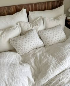 an unmade bed with white linens and pillows