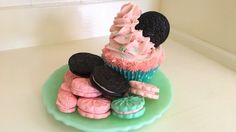 a green plate topped with lots of cupcakes and cookies on top of each other