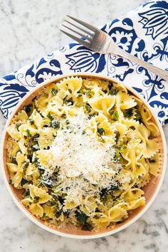 a bowl of pasta with spinach, cheese and parmesan on the side