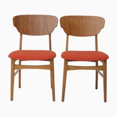 two wooden chairs with red upholstered seats on each side, one is facing the other