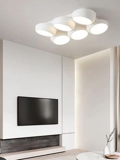 a modern living room with white walls and ceiling lights above the tv on the wall