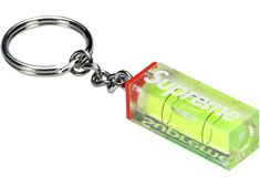 a green box shaped keychain with the word supreme on it's side