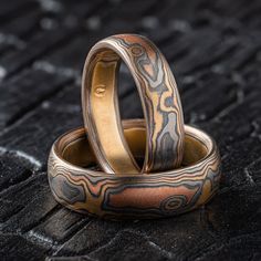 "* Price may vary depending on ring size, please inquire with us directly with your needed size for accurate pricing! This gorgeous Mokume Gane ring set features our Woodgrain pattern, varied finishes, and a Low Dome profile. This set is made with our \"Firestorm\" metal combination that contains 14k Red gold, 14k Yellow Gold, Palladium, and Sterling Silver. The highlight colors in this set feature palladium. Highlights vary with mokume and cant be guaranteed in this pallet.  Mokume Gane Band Set - Ring 1 Width Shown: 5mm Size Shown: 7 Pattern: Woodgrain  Palette: Firestorm  Finish: Etched & Oxidized Profile: Low Dome  Mokume Gane Band Set - Ring 2 Width Shown: 6mm Size Shown: 9.25 Pattern: Woodgrain  Palette: Firestorm Finish: Etched & Oxidized Profile: Low Dome  Price does NOT include st Modern Etched Jewelry For Wedding, Fusion Style Promise Jewelry, Artisan Etched Jewelry For Wedding, Unique Etched Jewelry For Wedding, Unique Etched Wedding Jewelry, Artisan Engraved Rings For Formal Occasions, Artisan Engraved Wedding Rings, Luxury Wedding Jewelry With Unique Variations, Artisan Hand Forged Wedding Rings