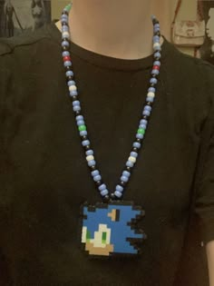 a person wearing a black shirt and necklace with an image of a pacman on it