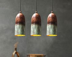 three brown and green lights hanging from a ceiling in a room with a table next to it