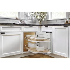 an open cabinet in a kitchen with white cabinets