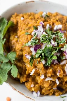 a white bowl filled with food and garnished with cilantro, red onion, and parsley