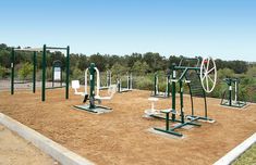 an outdoor gym area with various equipment in the middle and trees in the back ground