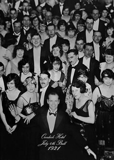 an old black and white photo of a group of people dressed in formal wear, posing for the camera