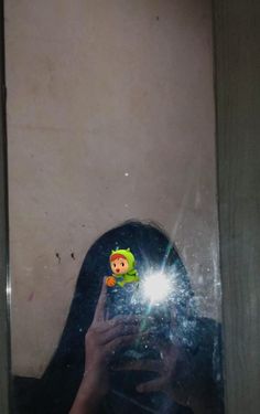 a woman taking a selfie in front of a mirror with a small doll on it