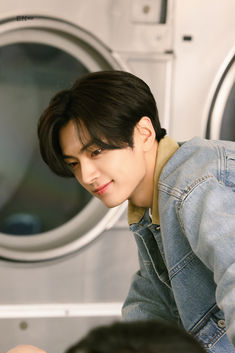 a young man is looking at something in front of a washing machine