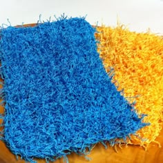 two blue and yellow rugs sitting on top of a wooden table next to each other