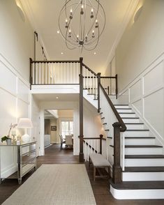 a large foyer with stairs and chandelier next to a white staircase leading up to the second floor