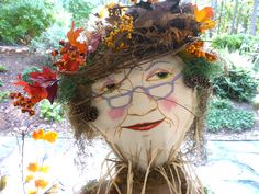 a statue with flowers and leaves on it's head