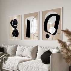 three black and white paintings hang on the wall above a couch in a living room