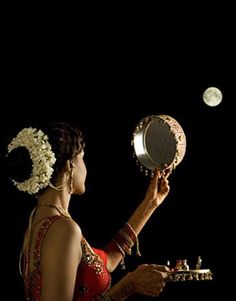 a woman is holding a mirror and looking at the moon