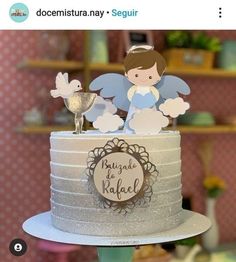 there is a cake that has angel decorations on the top of it and an angel figurine sitting on top