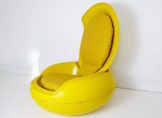 an inflatable yellow chair is sitting on the floor next to a white wall