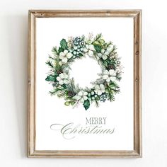 a christmas wreath with white flowers and greenery on it is hung in a wooden frame