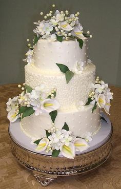 a wedding cake with white flowers and green leaves