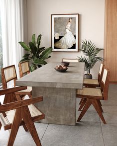 a dining room table with chairs around it and a painting on the wall behind it