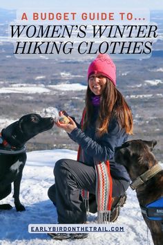 a woman sitting on top of a snow covered slope next to two dogs eating food