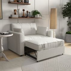 a living room with a white couch and small table in front of the wall is a potted plant