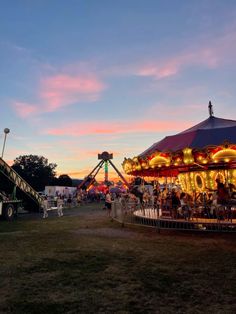 an amusement park at sunset with people on the rides and carousels in the background