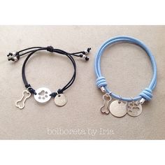 two bracelets with charms on them sitting next to each other