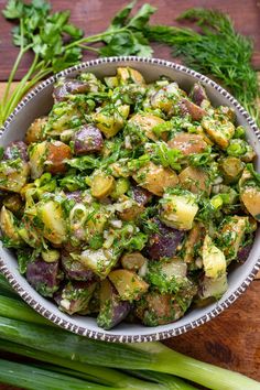 a bowl filled with potato salad on top of a wooden cutting board next to celery