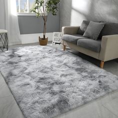 a living room area with a couch, chair and rug on the floor in front of a window