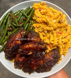 a plate with pasta, green beans and chicken wings