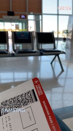 a ticket sitting on top of an airport floor next to empty chairs in the background