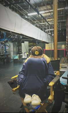 a man sitting in a chair with his back turned to the camera and wearing a hat