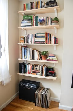 a bookshelf filled with lots of books next to a wall mounted record player