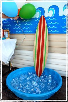 a surfboard sticking out of the top of a blue bowl filled with water and balloons