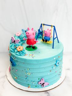 a peppa pig birthday cake with blue frosting and sprinkles