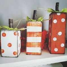 three painted pumpkins sitting on top of a white shelf