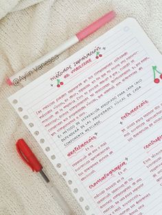 a red pen sitting on top of a white paper next to a notebook with writing