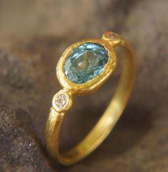 a gold ring with a blue stone in the middle and two diamonds on each side