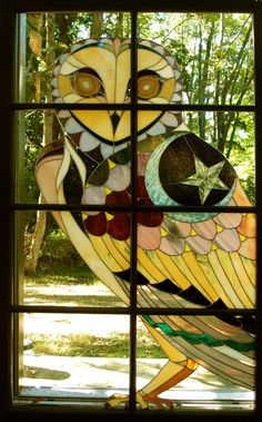 a stained glass owl sitting on top of a window sill